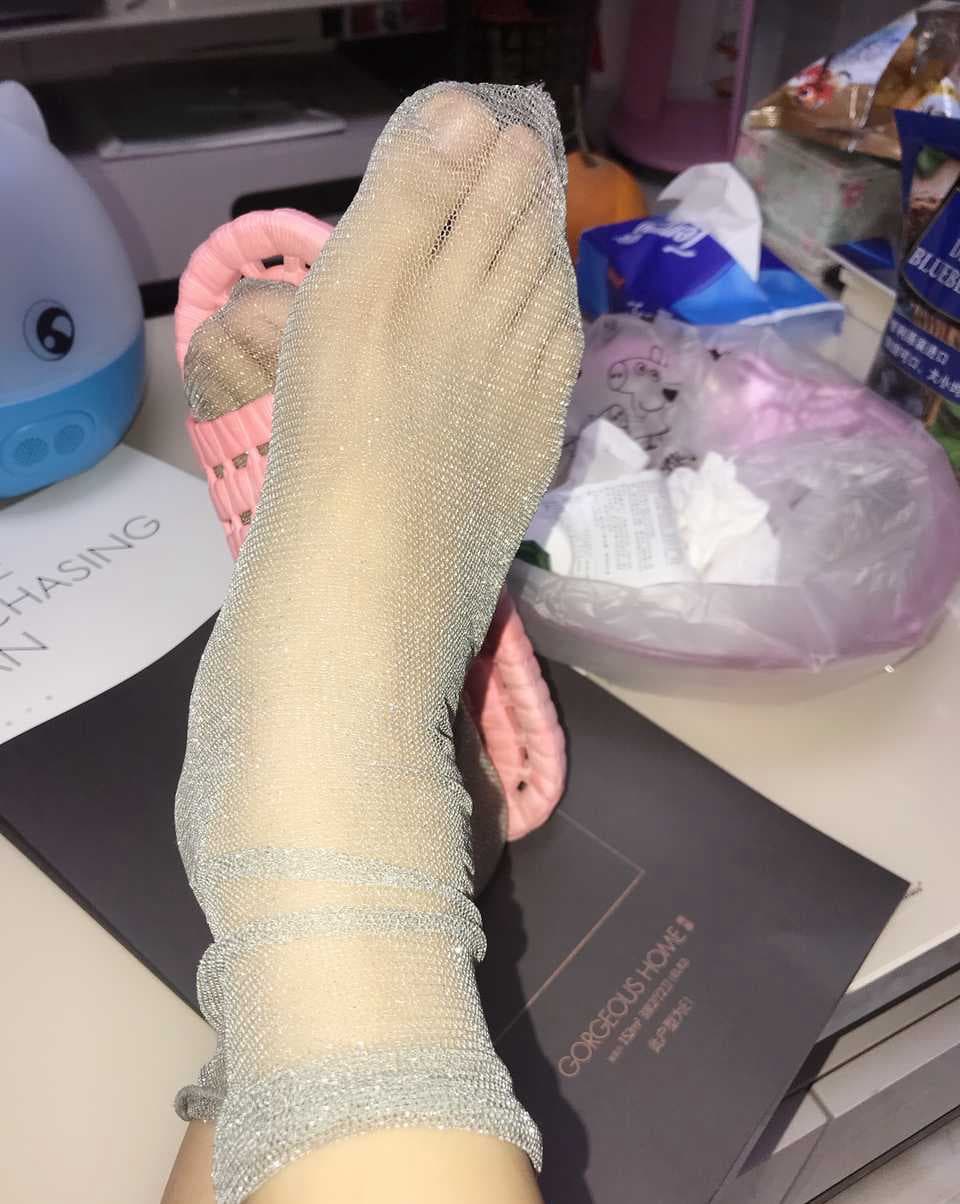 Macro view of glossy, stiff stockings stretched over toes and arch, light reflecting off a smooth, rigid surface.