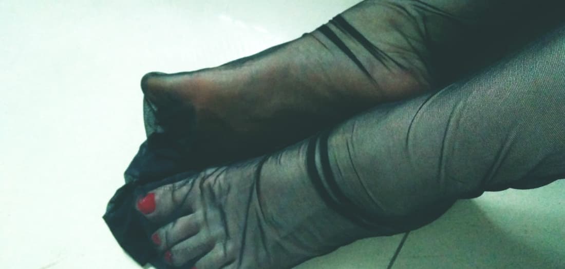 Model teasingly rolling down black stockings to reveal the top of a warm, soft sole