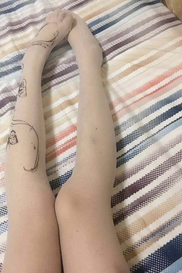 Nylon-clad foot posed on edge of chair, glossy fabric hugging the curve of the arch