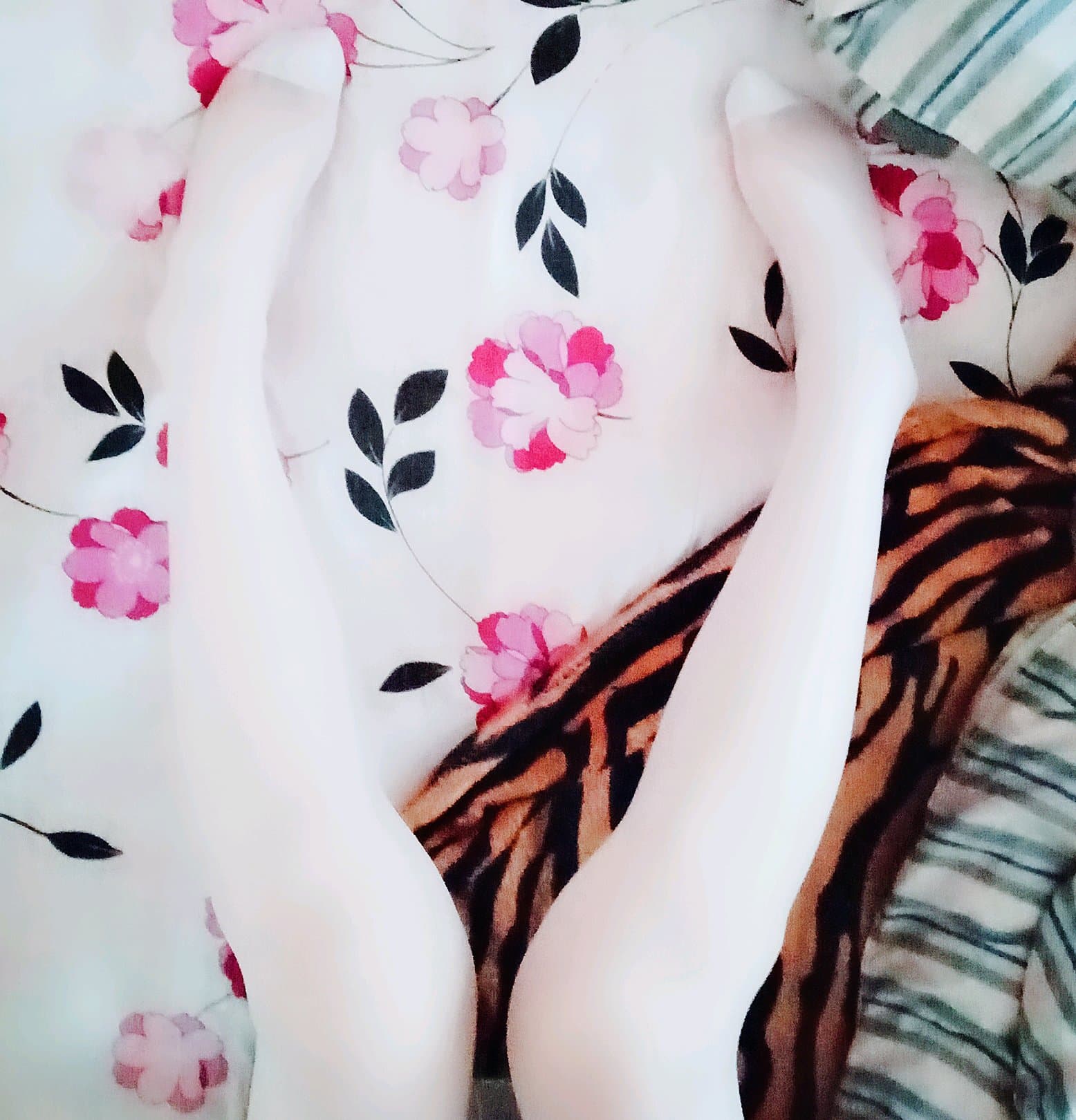 Cozy hotel room scene with removed shoes, stockings rolled down to calves, feet entwined on a bed