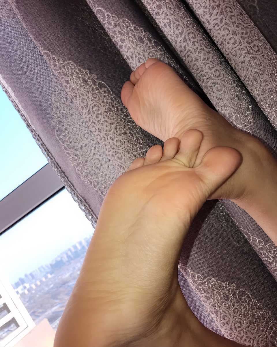 Intimate dining scene with legs under table, stockinged toes playfully pressing against bare foot