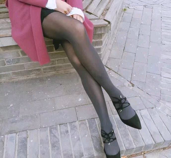 Close-up of sheer stockings on an ankle with autumn leaves, toes peeking from nylon edge teasingly