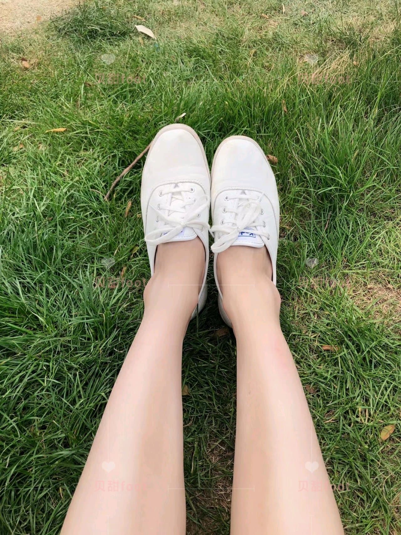 Woman sitting with legs relaxed, socks pushed down revealing bare soles and relaxed toes in a quiet resting moment.