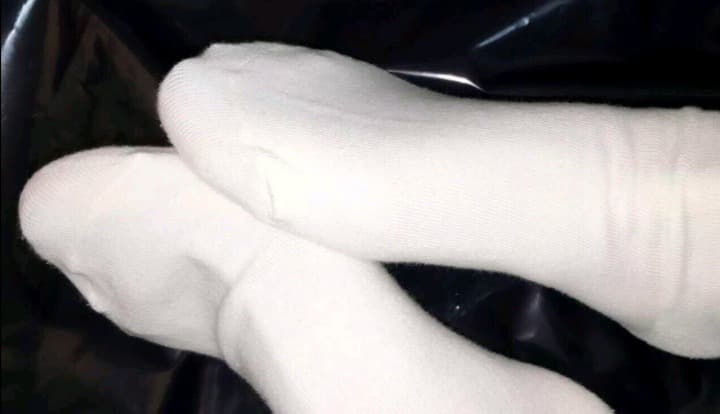 Pair of cotton socks half-pulled down around ankles, textured fabric and subtle creases visible