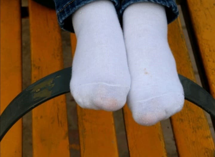 Shiny nylon-clad foot angled to highlight arch and glossy reflection under warm lighting