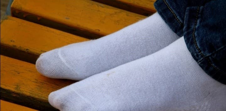 Bare foot resting beside a folded cotton sock, showing contrast of textures and natural curves