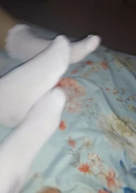 Blurry silhouette of a stocking-clad foot posed on a cushion, sheen and arch suggested rather than sharply defined