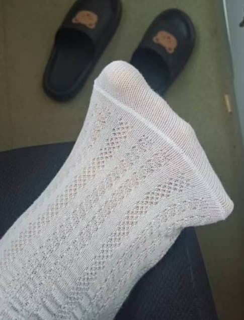 Two sets of adult feet close together, one in cotton socks and one bare, lit softly to suggest gentle interaction