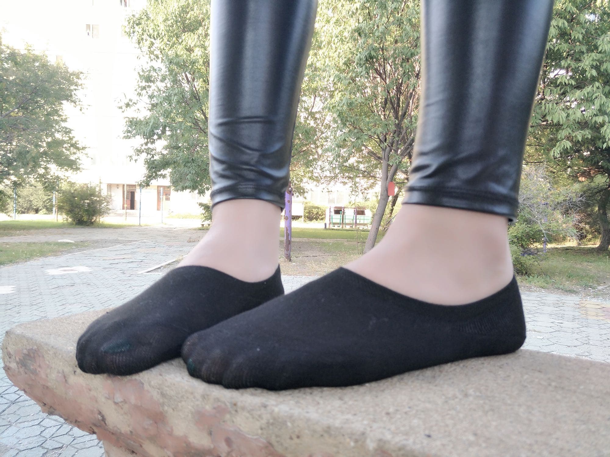 Close-up of a foot in soft cotton socks, toes pressing through fabric, heel slightly raised in teasing pose