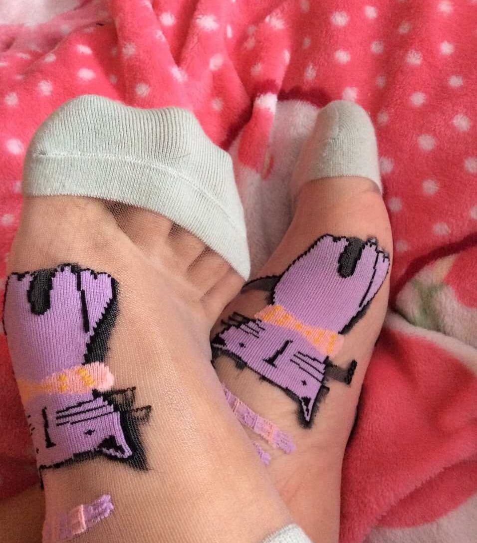 Petite woman in soft cotton socks showing a glimpse of bare toes and a hint of sole, exuding coy intimacy