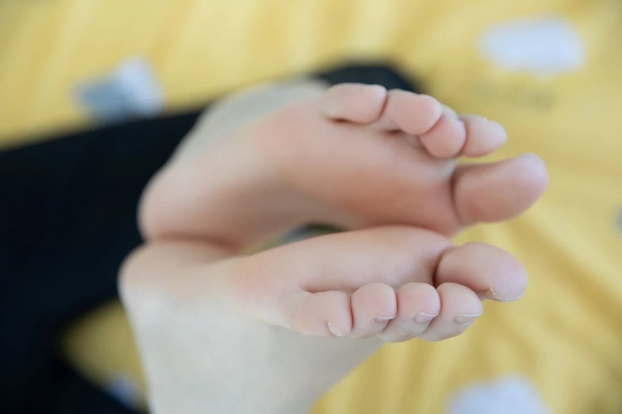 Casual scene of bare feet resting beside folded stockings, hinting at a lazy, intimate moment and soft textures