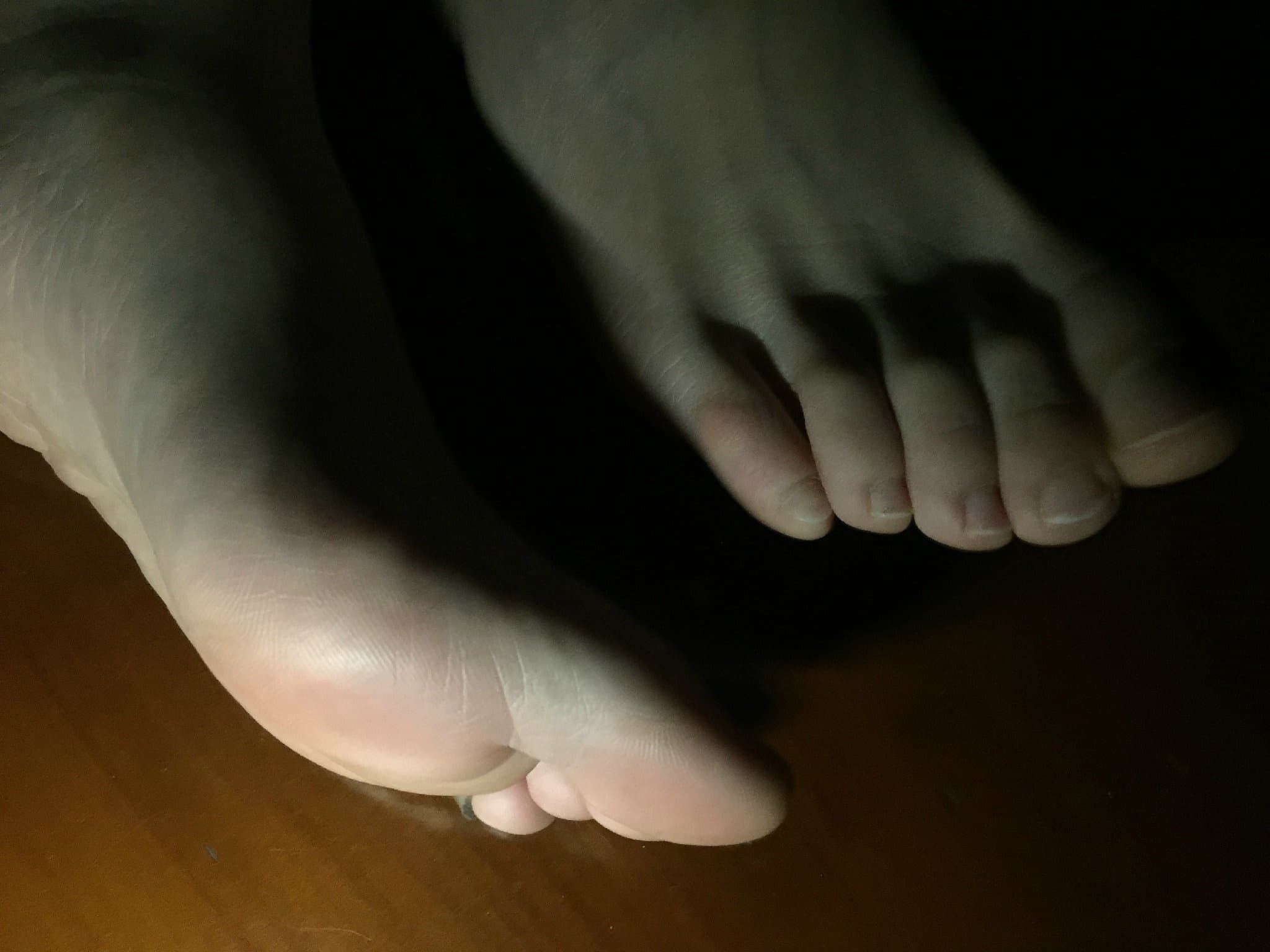 Moonlit bare feet and sheer stockings on soft sheets, toes luminous in shadow