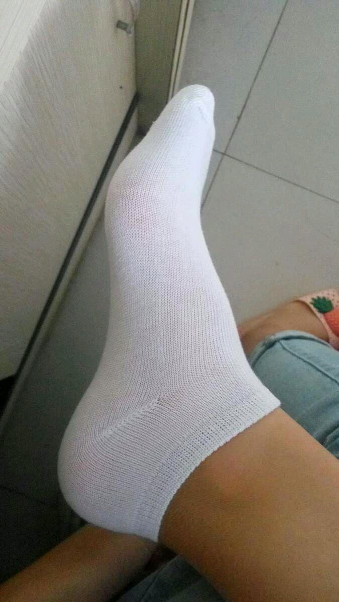 Discarded nylon stockings lying beside bare feet on a soft surface, hinting at recent removal and lingering scent