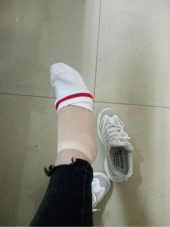 Young woman in a parked car pulling up cotton socks while revealing a hint of sheer stockings beneath her skirt