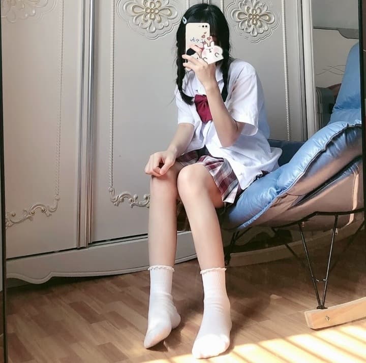 Close shot of stockings and bare ankle peeking from a pleated skirt, playful adult cosplay atmosphere