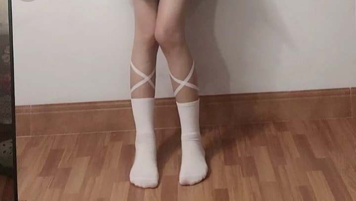 Pair of slightly worn cotton socks draped over a footrest, soft threads and a hint of cozy warmth visible