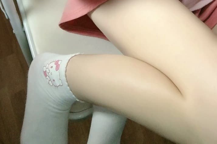 Man tracing the arch of a woman's foot as nylons gather around her ankles, soft lighting and warm tones