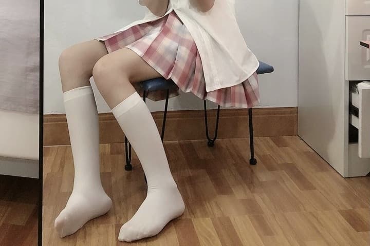 Softly lit portrait of silk stockings gathered at the ankle, smooth calf and elegant arch inviting a touch