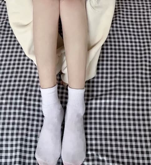 Close-up of soiled heel area on white socks, gentle creasing and subtle discoloration from extended use