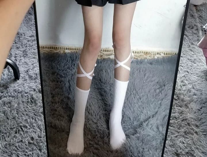 Pair of cotton socks lying together with subtle wet sheen and disheveled fabric hinting at recent intimate use