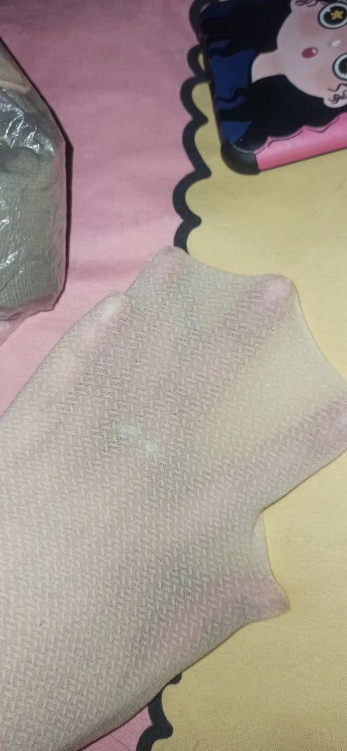 Low-angle shot of socks peeking out from under a skirt, showing creased fabric and relaxed barefoot pose