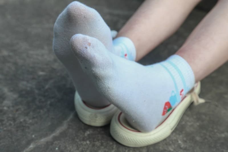 Cozy white socks snug around feet on a sofa, threads softened from wear