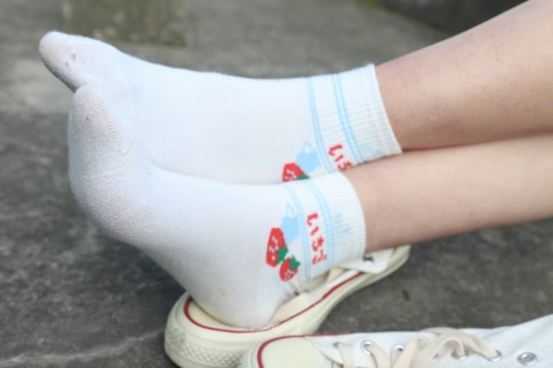 Close-up of toes in white cotton socks, heel slightly raised and fabric creased