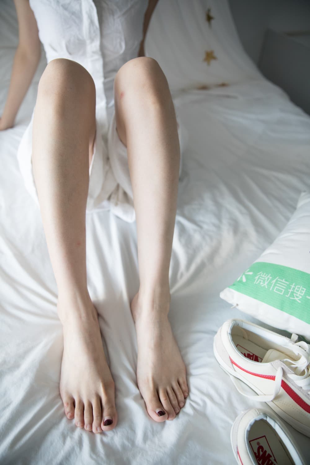 White skirt lifted slightly by breeze, bare foot and ankle revealed with delicate, suggestive pose